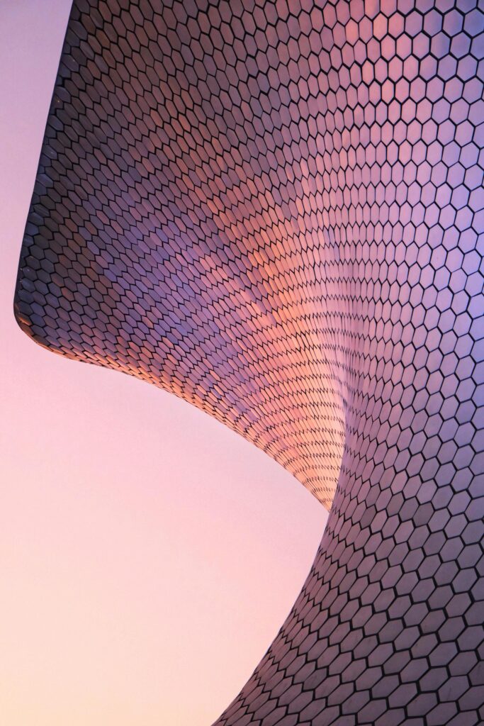 Elegant curves and hexagonal pattern of Soumaya Museum, CDMX captured against a vibrant sunset.
